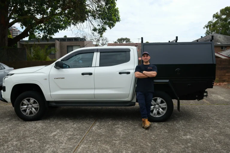 A Goliath Pest Solutions technician beside a branded service vehicle at a job site.