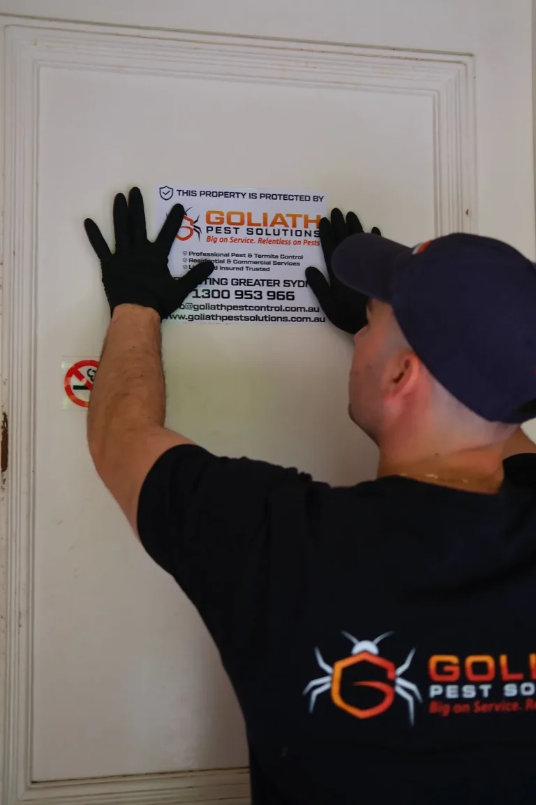 A technician applying a Goliath property-protection notice after service work.