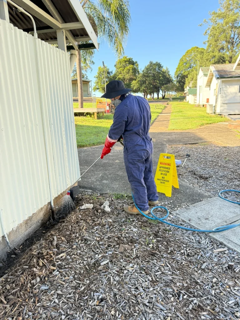 A technician carrying out external treatment work around a building perimeter.