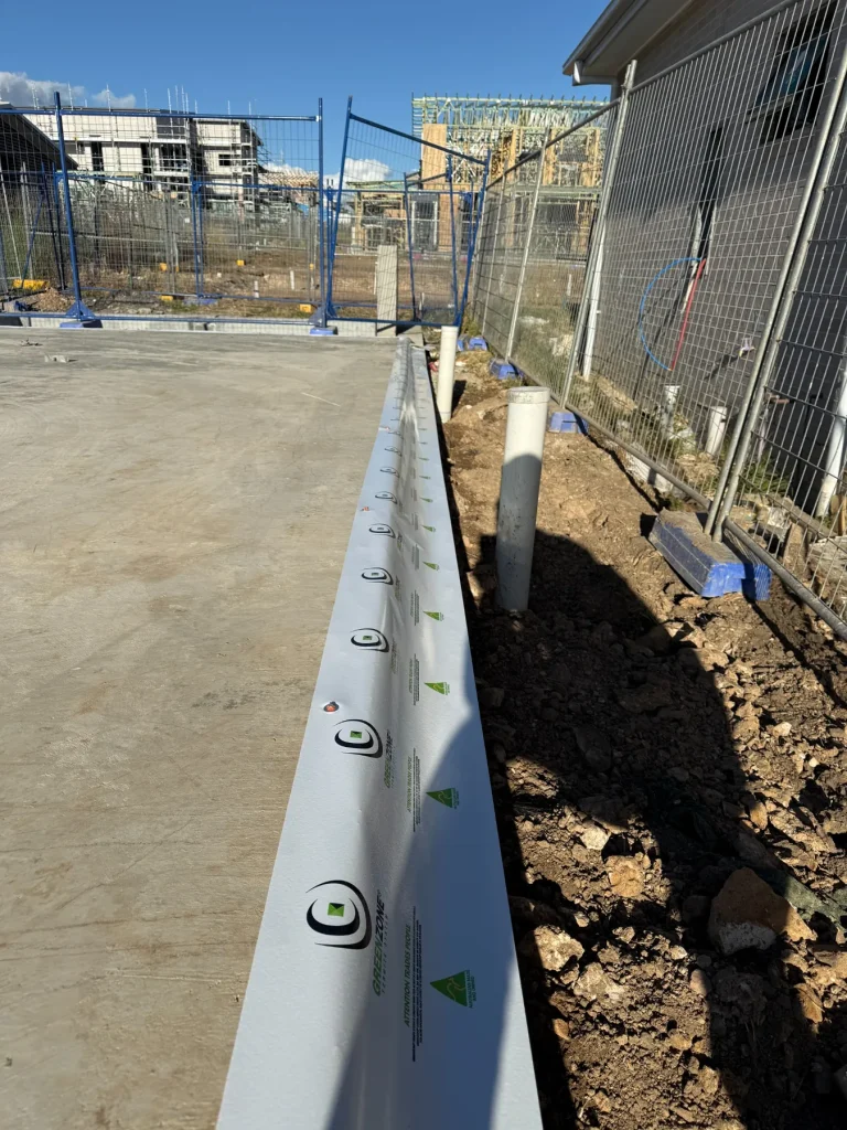 Perimeter termite-management work installed alongside a new concrete slab.