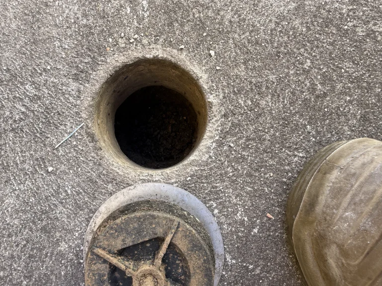 A prepared drill point in paving during post-construction termite barrier work.