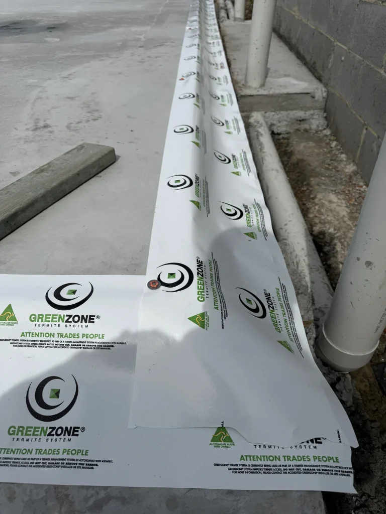 Termite-management material installed along a slab perimeter during construction.