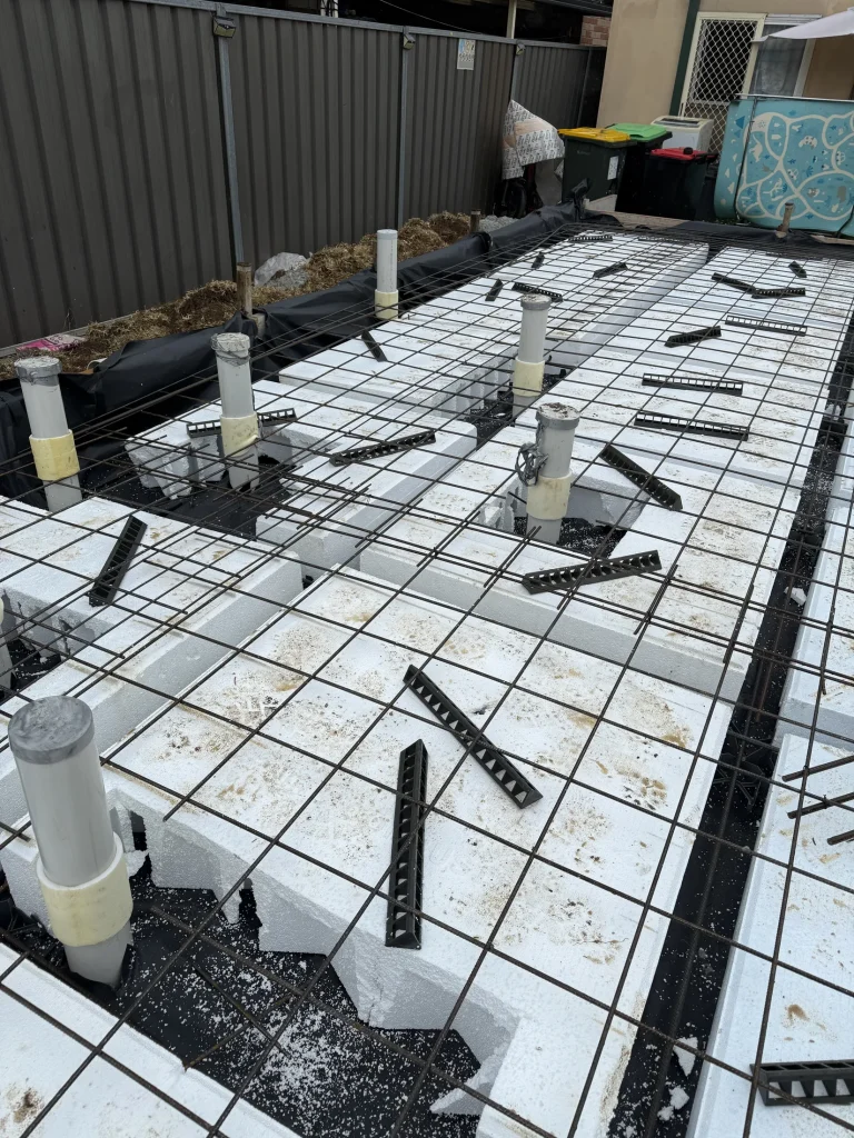 A broad view of slab reinforcement and service penetrations during pre-construction termite-management work.
