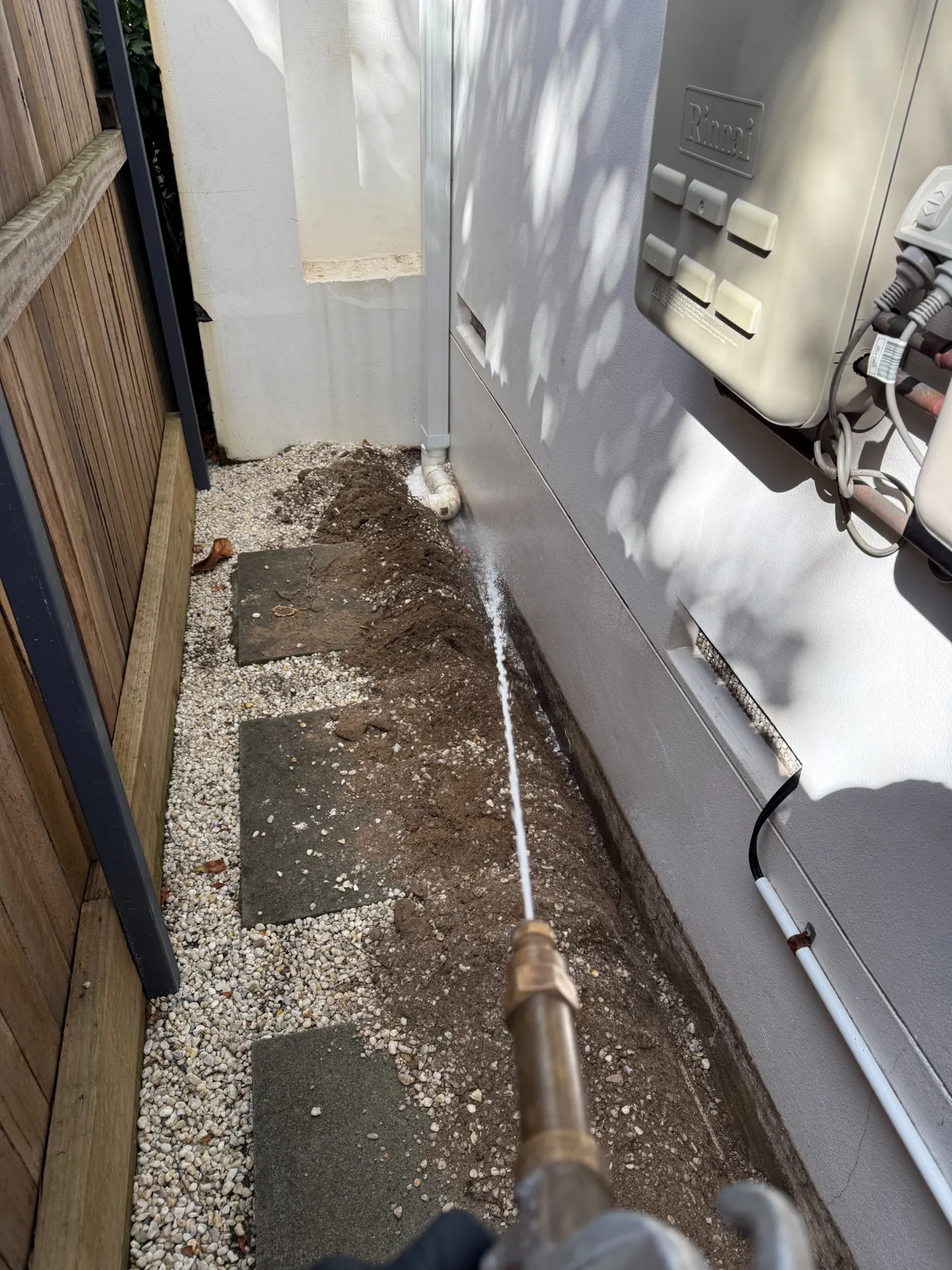 Technician applying liquid termite soil treatment into a perimeter trench beside a Maroubra home